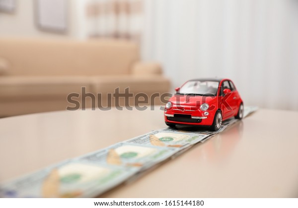 Miniature automobile model and money on table\
indoors, space for text. Car\
buying
