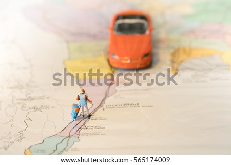 Miniature backpacker on map with super car using as background travel or business concept.