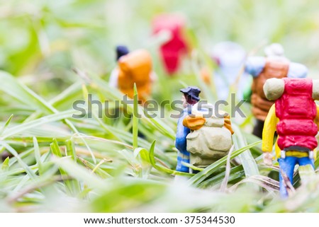 Miniature backpackers walking on the grass