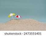 Miniature beach umbrella on beach sand with copy space