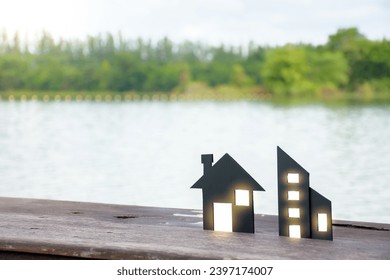 Miniature black house model and commercial building model with dot soft light on wooden planks over green forest and sky background at lake outdoor for concept of home insurance and real estate. - Powered by Shutterstock