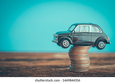 Miniature Black Second Hand Car Model On Coins Stack On Wooden Table. Business, Finance Or Budget Plan Money Saving For Buying A Used Car And Auto Insurance Concept. Road Trip For Holiday Traveling.