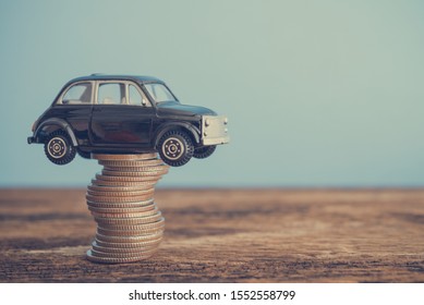 Miniature Black Second Hand Car Model On Coins Stack On Wooden Table. Business, Finance Or Budget Plan Money Saving For Buying A Used Car And Auto Insurance Concept. Road Trip For Holiday Traveling.