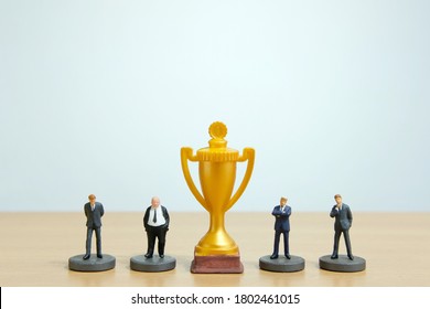 Miniature Business Concept - Businessman Lineup Based On Rank With Golden Trophy In The Middle