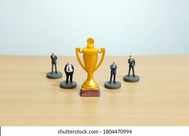 Miniature Business Concept - Businessman Lineup Based On Rank With Golden Trophy In The Middle