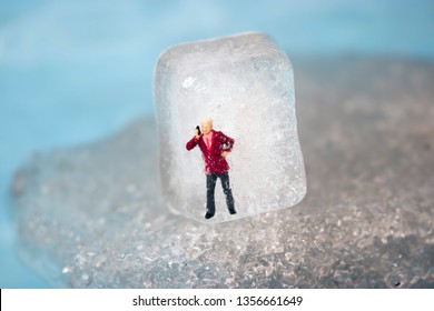 Miniature Business Man Frozen In Time Talking On His Outdated Cell Phone. Ice Man Trapped By Modern Technology. Boss Or Employee Is Left Out In The Cold. Problems Working In Tech. Man Chilling Out.