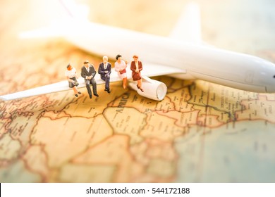 Miniature business people : businesses team sitting on airplane wing for travel around the world, business trip traveler adviser agency or transportation to explorer on earth background concept.