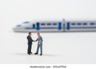 Miniature Business People Shaking Hand To Make Agreement With High Speed Train Model Background