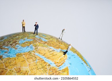 miniature business people stand spread out on a globe in different countries. White background - Shutterstock ID 2105864552