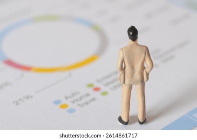 Miniature Businessman Analyzing Colorful Pie Chart on White Background
