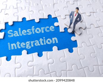 Miniature businessman on a white puzzle with text Salesforce Integration.
