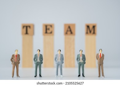 Miniature Businessman On Wood Blocks And Word TEAM Build Be Wooden Blocks On White Background.teamwork For Brainstorming Together, No People, Business Concepts.