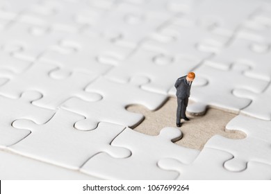 Miniature businessman stand on white jigsaw. One jigsaw are missing from board. Business vision concept. - Powered by Shutterstock