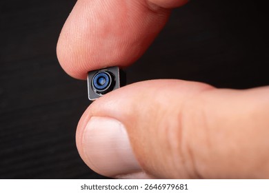 Miniature camera with tiny lens in hand, showcasing its intricate details and technology.