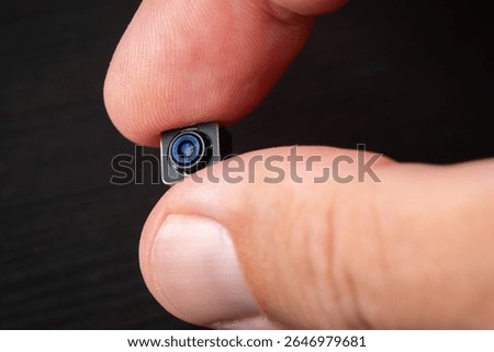 Miniature camera with tiny lens in hand, showcasing its intricate details and technology.
