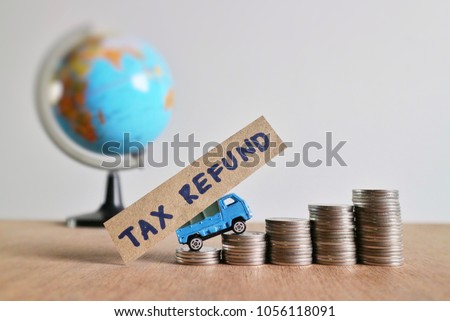 Miniature car carry paper with “tax refund” word and drives on roll increasing ladder of coin money on wood table in blur world globe on white background