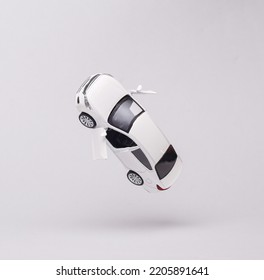 Miniature car model flying in antigravity on gray background with shadow. Levitation object in the air. Creative minimal layout