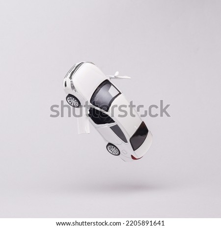 Miniature car model flying in antigravity on gray background with shadow. Levitation object in the air. Creative minimal layout