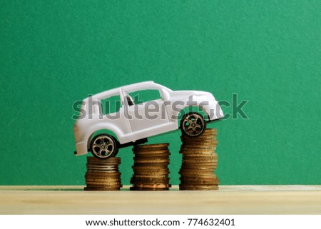 Miniature car on coin stack. Auto transportation conceptual.