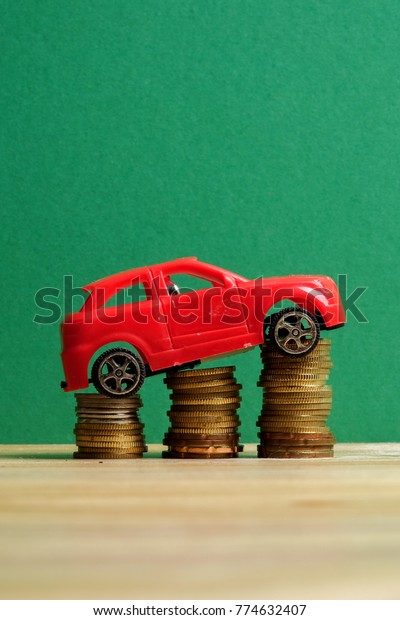 Miniature car on coin stack. Auto\
transportation\
conceptual.