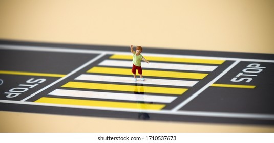 A Miniature Child With A Hand Raised Crossing A Crosswalk.