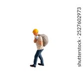 Miniature construction worker  carrying a heavy sack on his back isolate on white background with clipping path