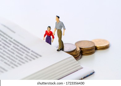 Miniature couple walking up stacked coins onto a book in a concept of financial barriers to higher education, study and career over a white background with copy space - Shutterstock ID 1723356430