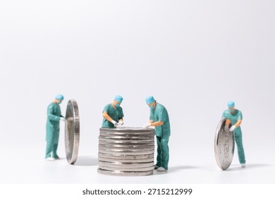 Miniature doctors examining a stack of coins on white background, healthcare finance and medical cost concept with teamwork and planning.