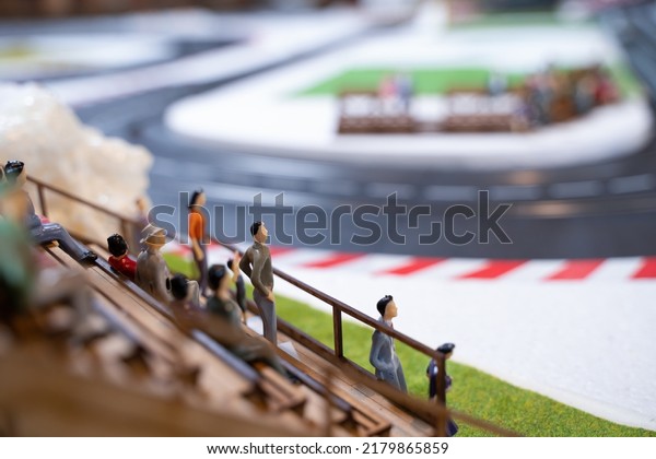 Miniature doll in race track,\
Miniature people watching racing cars in the field. Selective\
focus