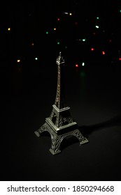 Miniature of the Eiffel Tower. In the dark - a ray of light from above and against the background of shining garlands. Eiffel Tower in the New Year. Macro photography. 