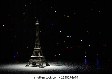 Miniature of the Eiffel Tower. In the dark - a ray of light from above and against the background of shining garlands. Eiffel Tower in the New Year. Macro photography. 