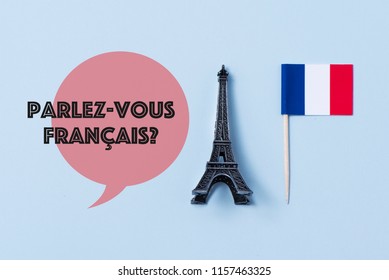 a miniature of the Eiffel Tower, a flag of France and the question parlez-vous francaise, do you speak French? written in French, against an off-white background