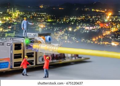 Miniature Engineer Working On The Motherboard Of Computer With Network Cable Blending With Panorama Of Phuket City At Night