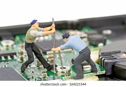 Miniature engineers repairing a computer hard drive