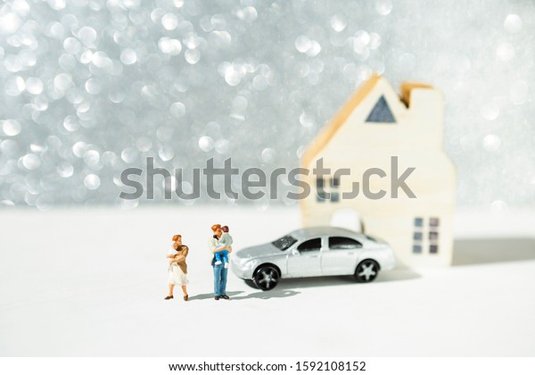 Miniature family with\
car and house over blurred silver bokeh background, building\
family, property\
business
