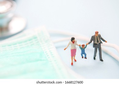 Miniature Figure Of Family With Surgical Mask To Protect Virus. Health And Medical Concept