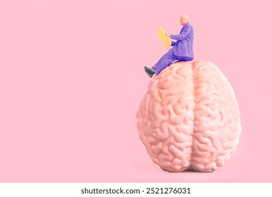 Miniature figure in purple suit reading a paper while perched on a large pink brain model against a soft pink background. Critical thinking concept. - Powered by Shutterstock