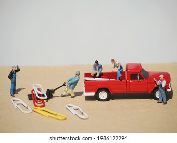 Miniature Figure Of Worker And Diecast Cars Toys On The Brown Table With White Background.