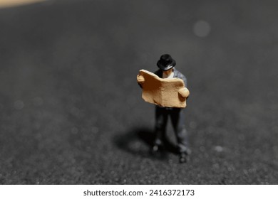 miniature figurine of a man reading newspaper