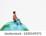 miniature figurine of a man sitting on the top of a world globe