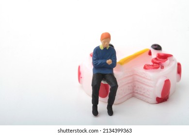 Miniature Figurine Of A Man Sitting On A Giant Cake 