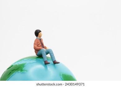 miniature figurine of a man sitting on the top of a world globe - Powered by Shutterstock