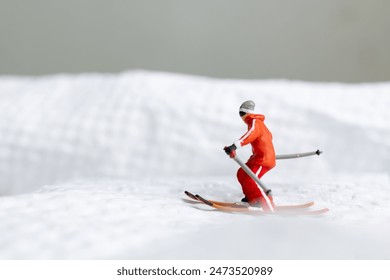 A miniature figurine of a skier dressed in vibrant winter gear. The skier is captured in motion, skiing across a white snowy landscape - Powered by Shutterstock