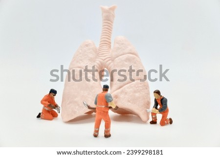 miniature figurines of men at work team on a huge pair of human lungs