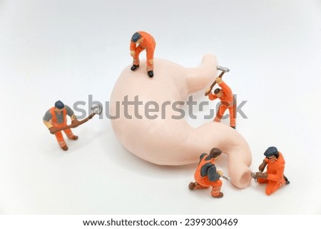 miniature figurines of men at work working on a huge human stomach