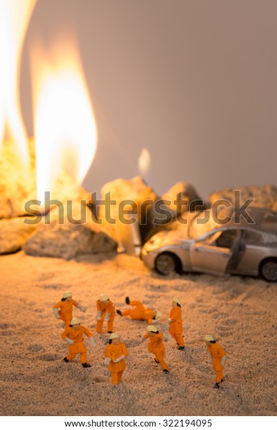 Miniature firemen\
at a car crash scene in\
flames