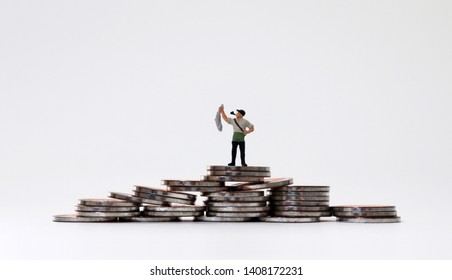 A miniature fisherman holding fish on coin piles.