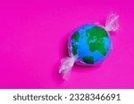 Miniature globe enclosed in plastic wrap like a candy. Working towards a cleaner and greener planet.