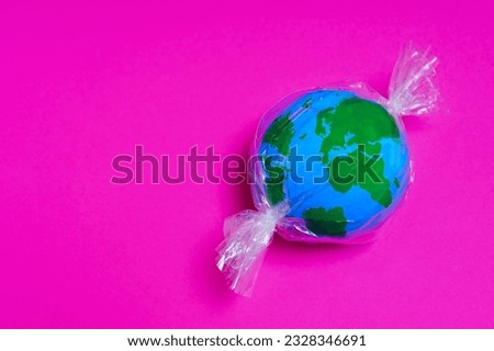 Miniature globe enclosed in plastic wrap like a candy. Working towards a cleaner and greener planet. Stock photo © 