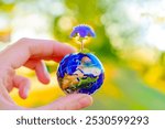 Miniature globe held in hand, featuring puzzle piece design, topped with vibrant flower, symbolizing environmental conservation and sustainability.